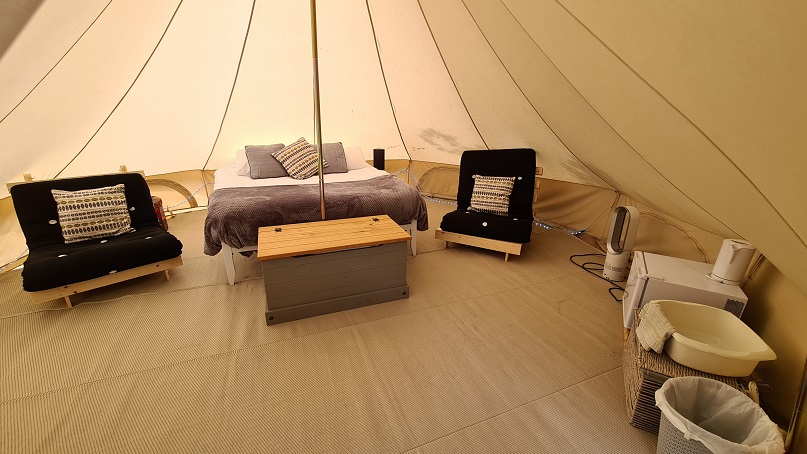 glamping bell tent interior with futons and double bed
